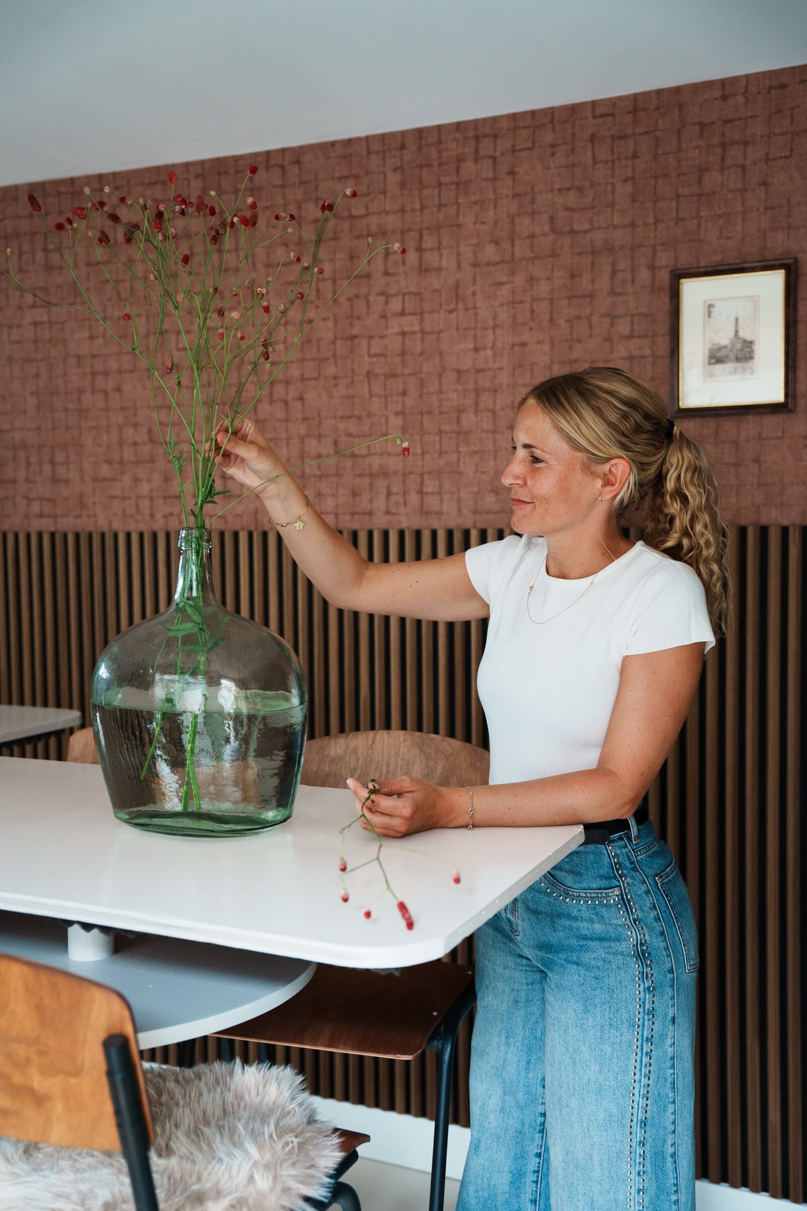 Nikki schikt bloemen in een grote vaas op een gedekte tafel