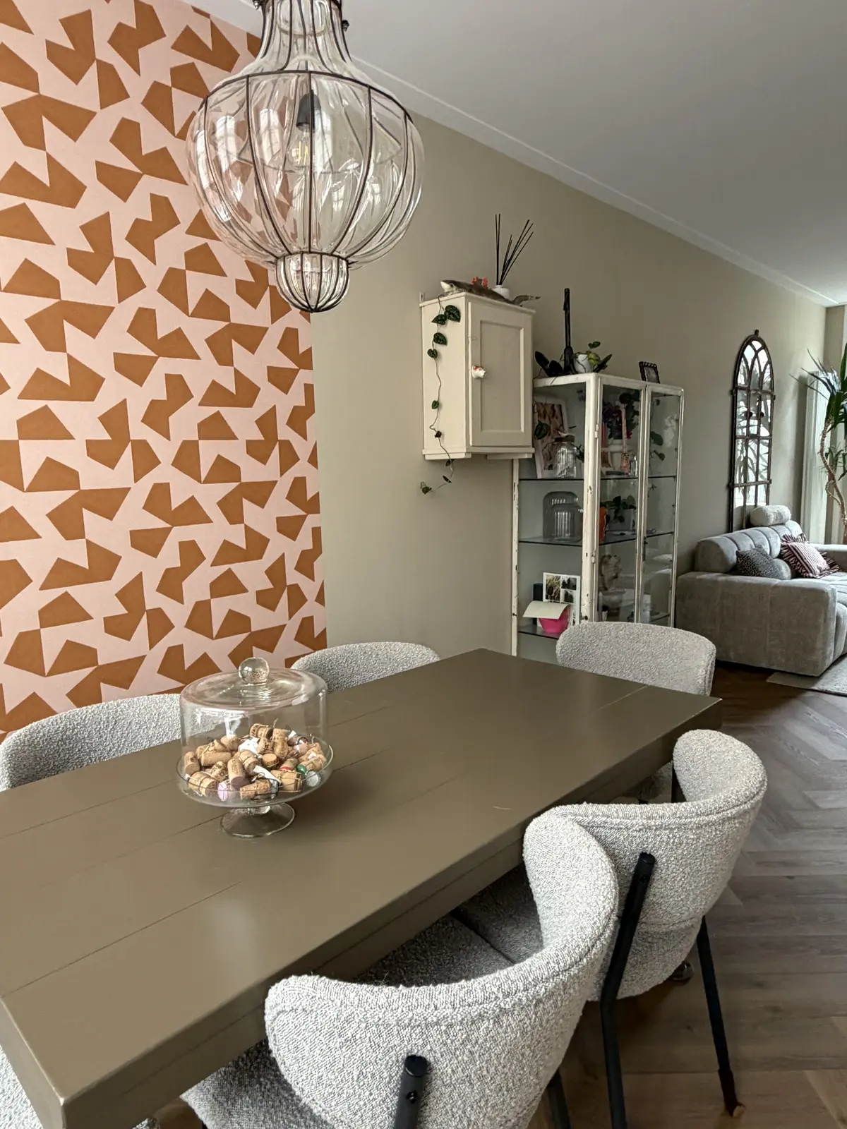 De eettafel na de make-over: bruin geschilderd, met bouclé stoelen en roze-oranje behang op de wand
