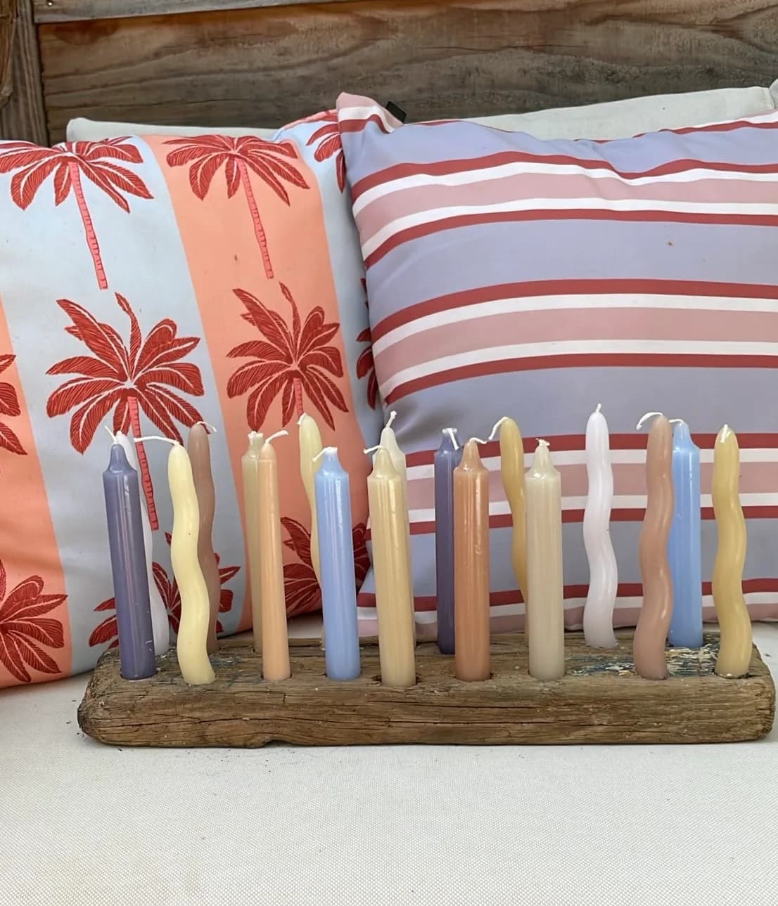 Zelfgemaakte kaarsenhouder van oud hout met pastelkleurige kaarsen op het dakterras
