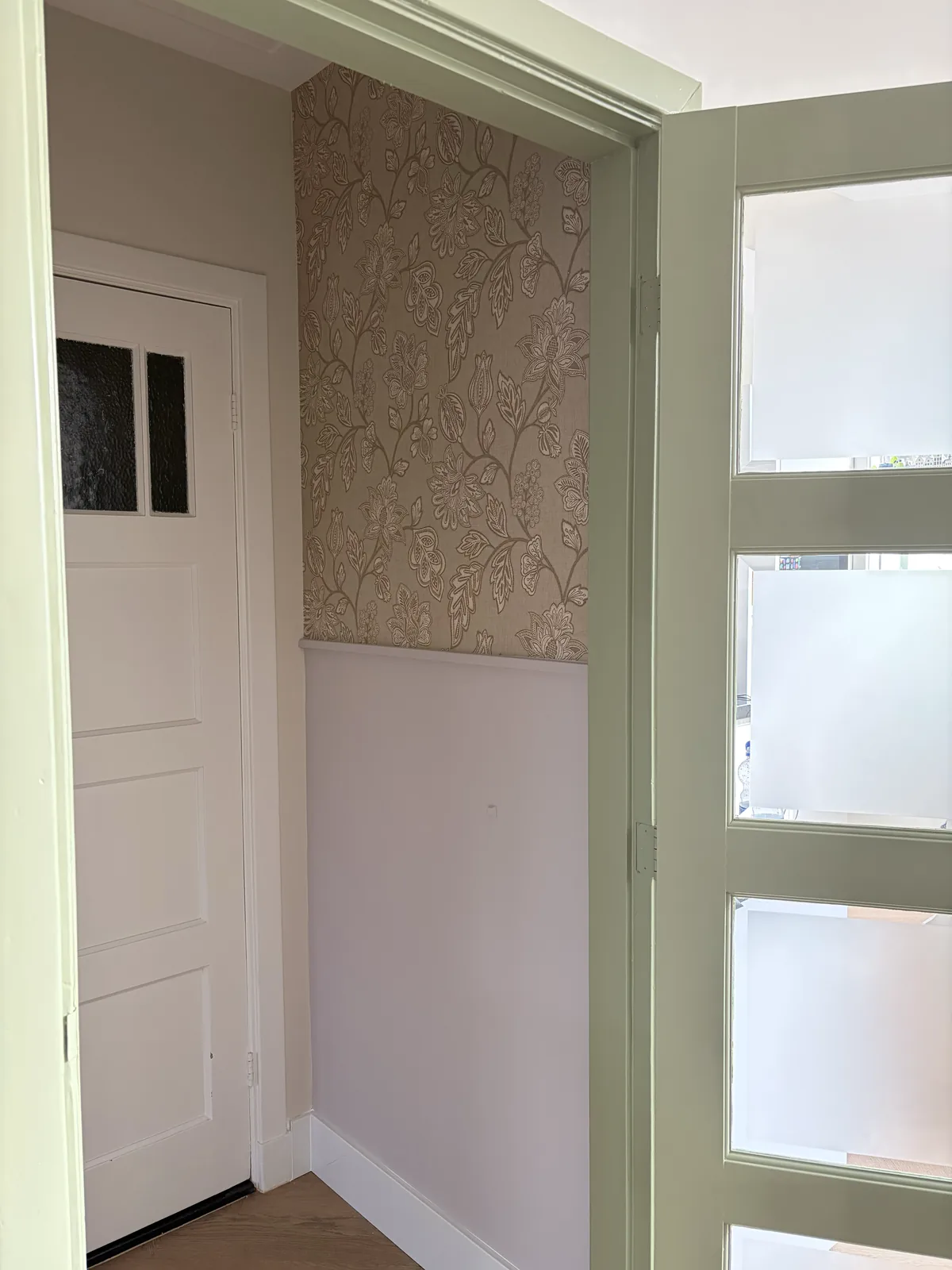 Entree met bloemenbehang en zachtgroen geschilderde deurkozijnen