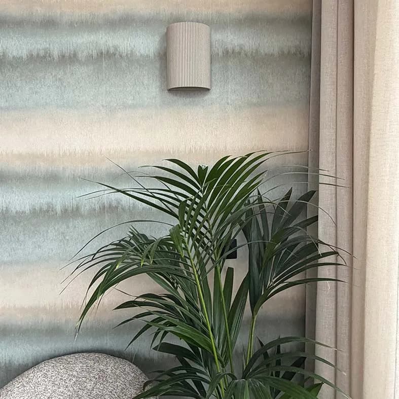 Wandbehang met zachte horizontale banen, met een kamerplant ervoor