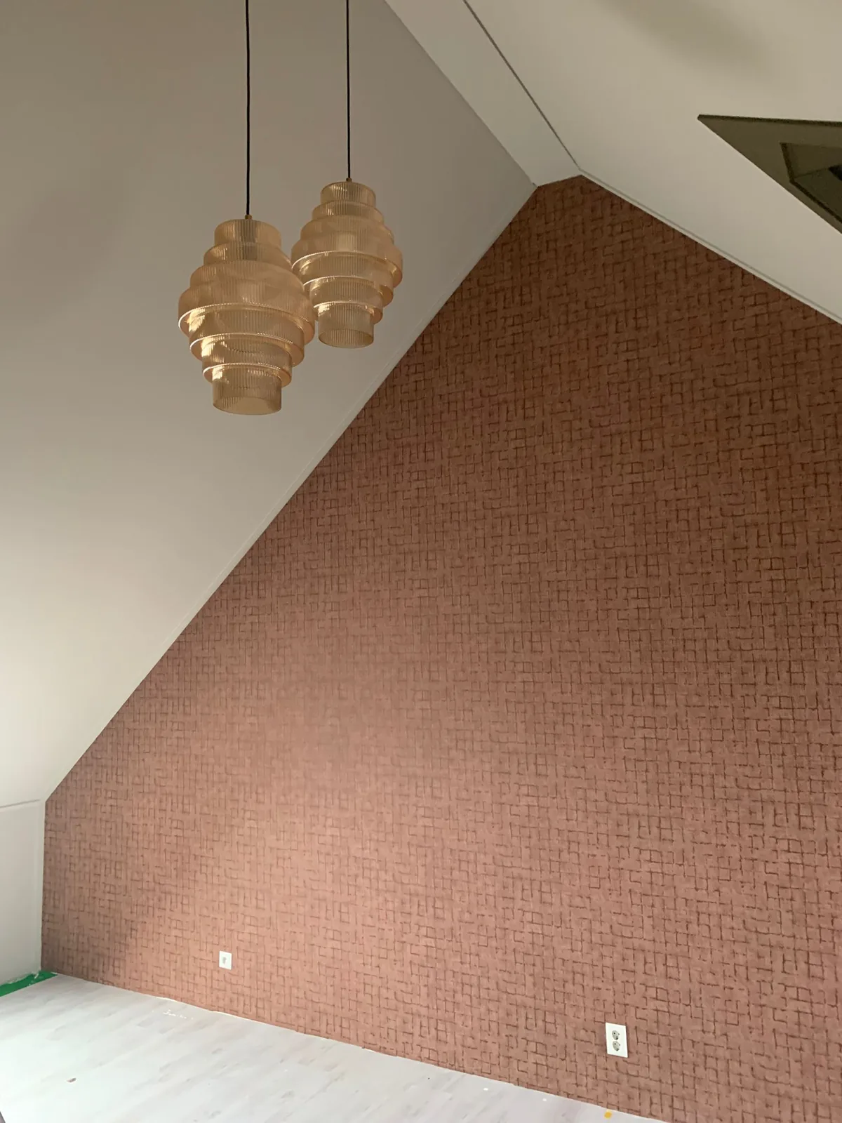 Zolder met terracotta behang, olijfgroen dakbeschot en twee gevlochten hanglampen